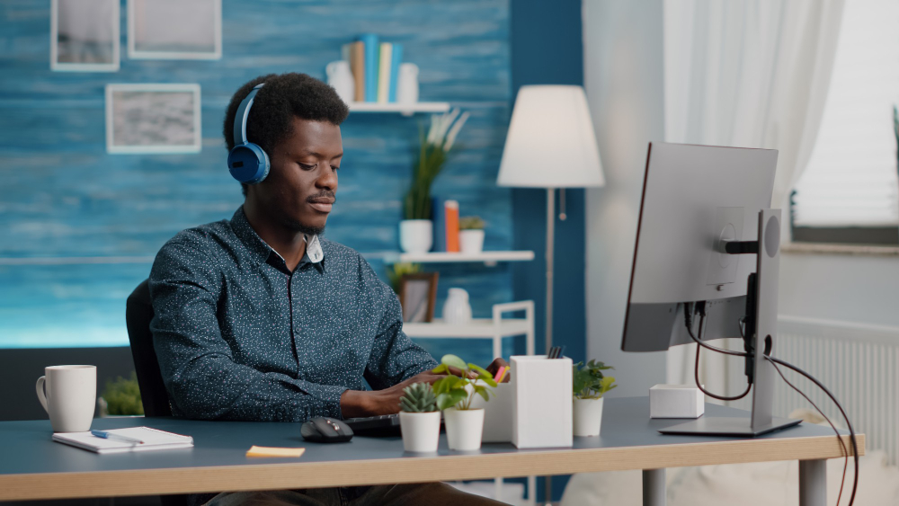 young manager using headphones listen music while working from home office computer pc